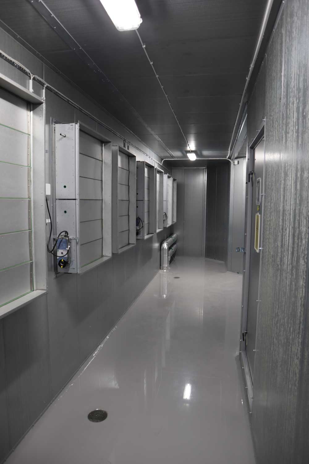 Ett fläktrum i en korridor, gråa väggar och golv.